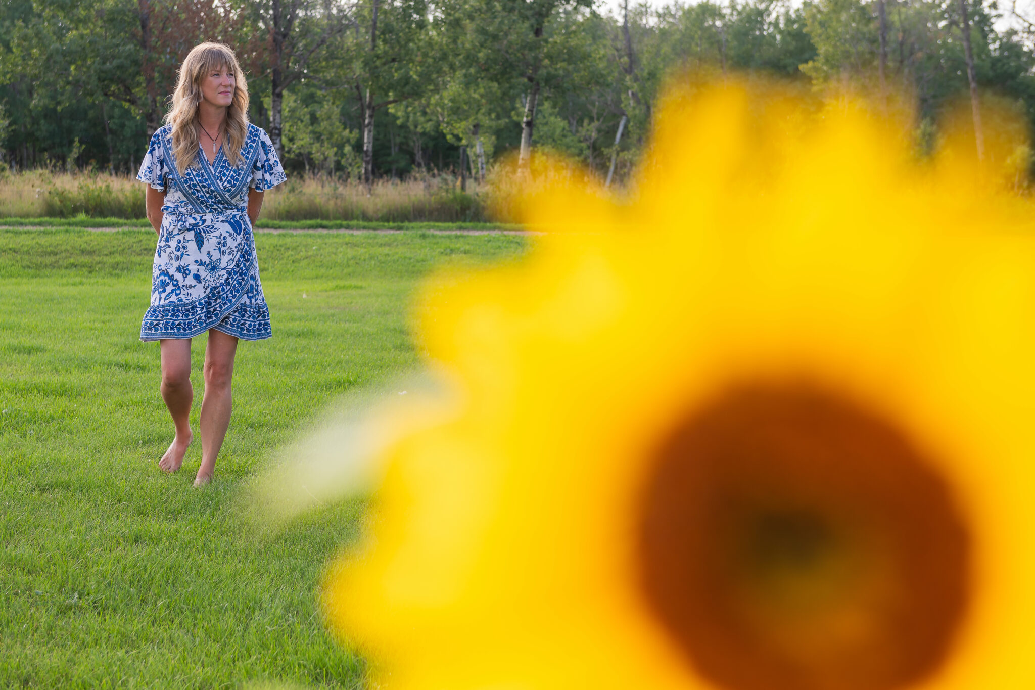 Life coach walking barefoot in a sunflower patch, surrounded by vibrant yellow flowers and a warm, natural light.