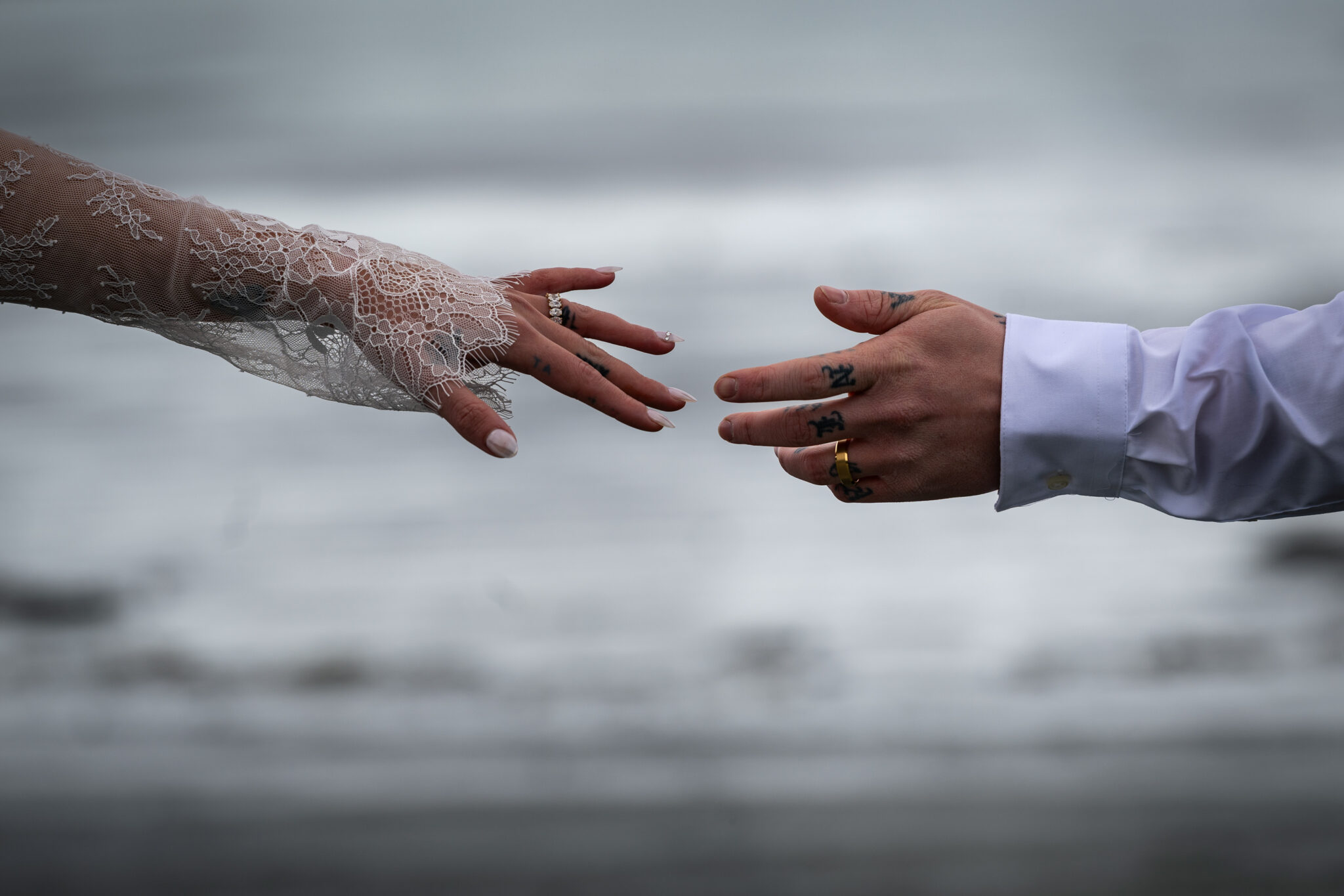 intimate beach wedding Tofino couple reaching for each other with ocean in background